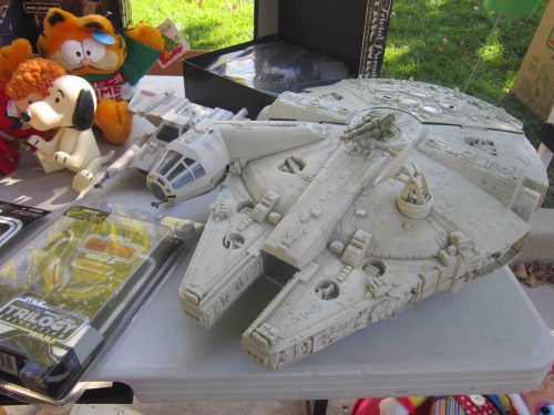 A detailed model of the Millennium Falcon surrounded by various toys, including plush characters and action figures.
