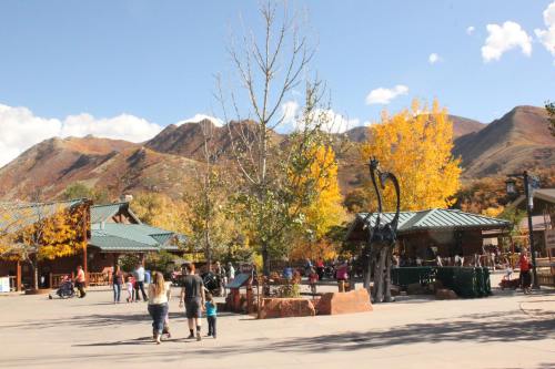 A scenic outdoor area with people walking, surrounded by colorful autumn trees and mountains in the background.