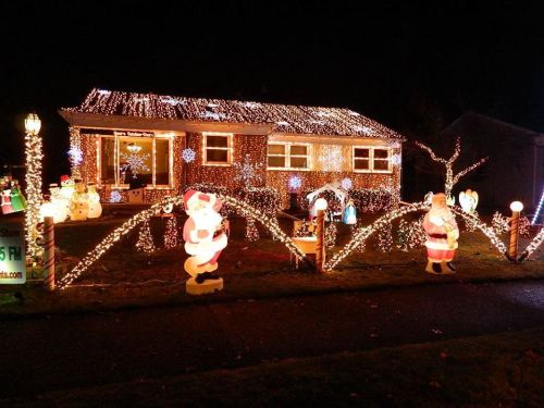 A house decorated with colorful Christmas lights, featuring Santa and snowman figures in the yard.