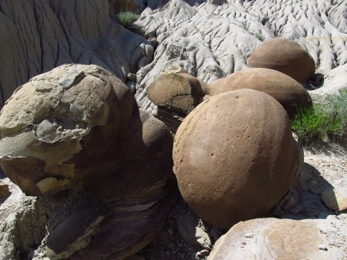 A rocky landscape featuring large, round boulders among textured, eroded earth formations.
