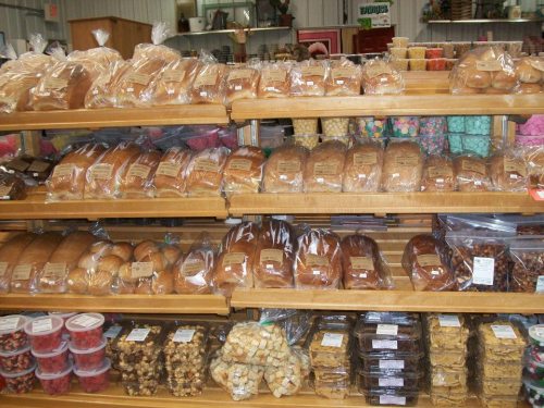 Shelves filled with various types of bread and snacks, all neatly packaged and displayed in a store.