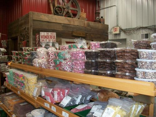 A colorful display of various candies and cookies stacked on shelves in a rustic store setting.