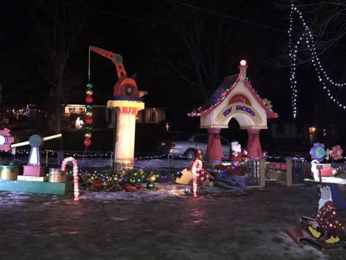 Colorful holiday decorations featuring a toy factory, crane, and festive lights in a nighttime setting.