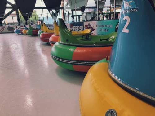 Colorful bumper cars lined up on a smooth surface in an indoor amusement area.