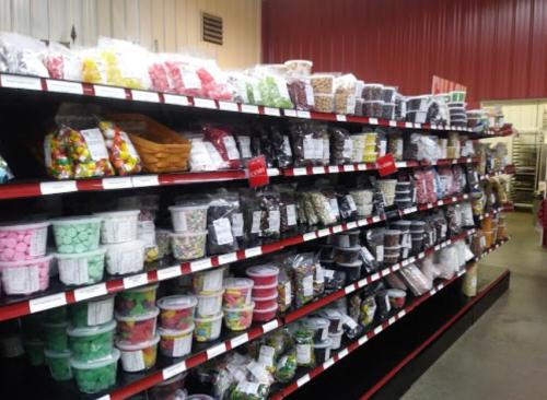 A colorful candy aisle with various jars and bags of sweets neatly arranged on shelves.