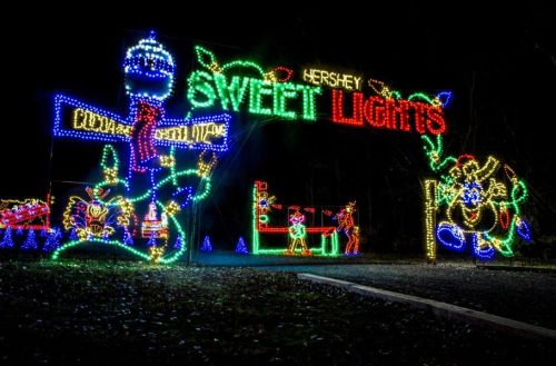 Colorful holiday lights display featuring "Hershey Sweet Lights" with festive characters and decorations at night.