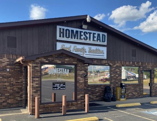 Exterior of the Homestead restaurant, featuring a wooden facade and a sign that reads "Food. Family. Tradition."