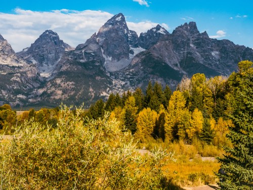 Scenic view of rugged mountains with autumn foliage and clear blue sky in the foreground.