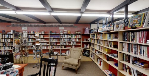 A cozy library with bookshelves filled with books and a comfortable armchair in the center.