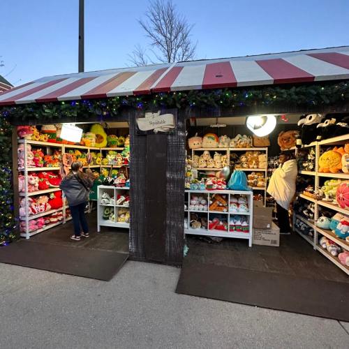 A festive shop filled with colorful plush toys, with customers browsing shelves under warm lights.