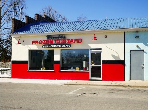 A colorful storefront of "Brenda's Frozen Custard" featuring a red and blue exterior, with large windows and a sign.