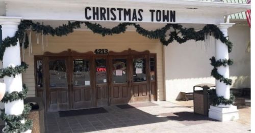 Entrance to "Christmas Town" decorated with garlands and icicles, featuring wooden doors and an "Open" sign.