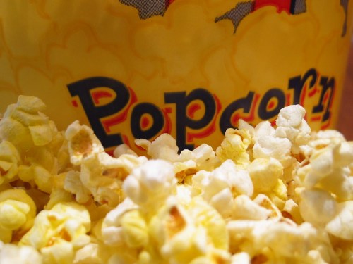 Close-up of buttery popcorn spilling out from a colorful popcorn container.