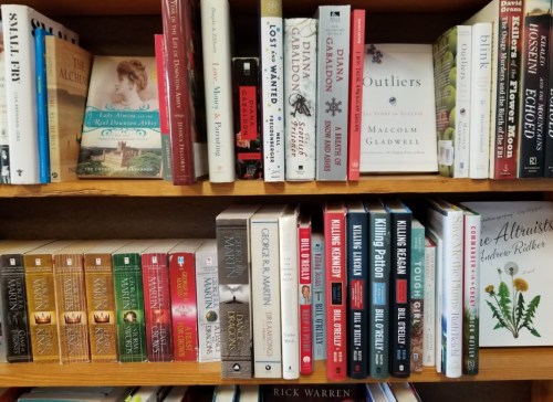 A wooden bookshelf filled with various books, including titles by Malcolm Gladwell and Rick Warren.