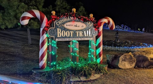 Sign for Chisholm Trail Boot Trail, decorated with candy canes and colorful lights at night.