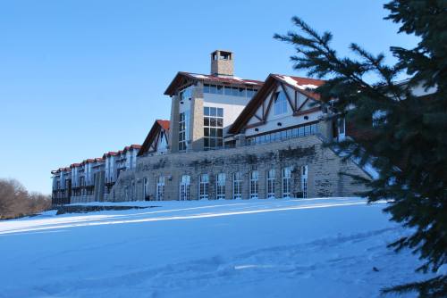 A large stone and wood building with a red roof, surrounded by snow and trees under a clear blue sky.