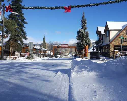 Snow-covered street lined with festive decorations and charming buildings under a clear blue sky.