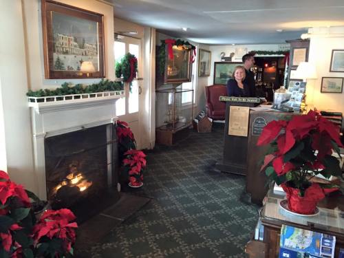 Cozy lobby with a fireplace, festive decorations, and a smiling receptionist at the front desk.