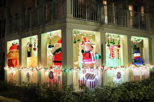 A festive display featuring inflatable Christmas characters, including Santa, a snowman, and a bear, adorned with lights.