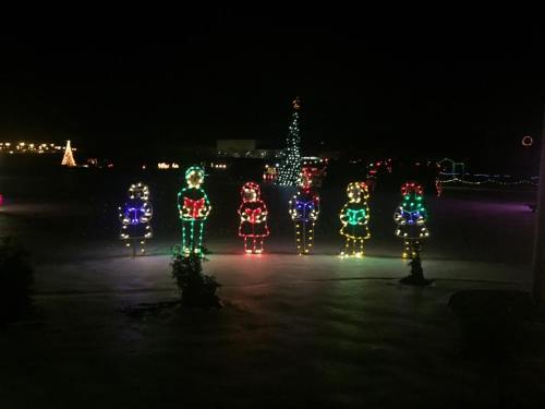Colorful Christmas light displays featuring six animated figures and a decorated tree at night.