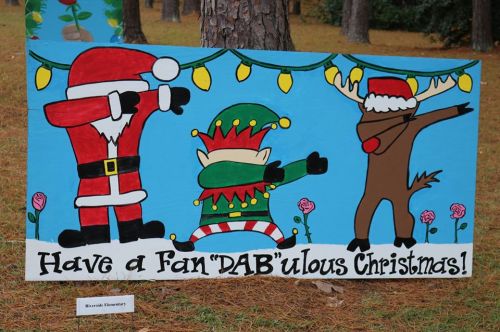 Colorful holiday sign featuring Santa, an elf, and a reindeer dancing with the text "Have a Fan 'DAB'ulous Christmas!"