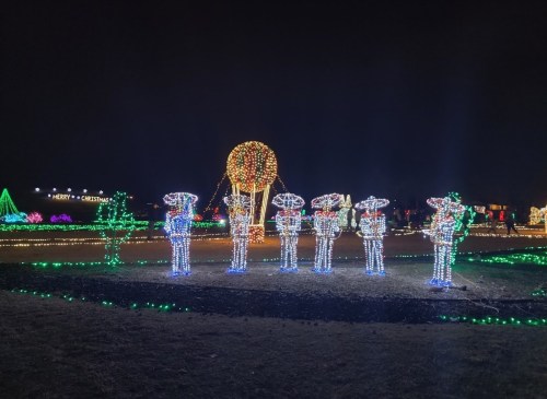 Colorful holiday lights display featuring illuminated figures and trees in a festive nighttime setting.