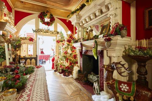 A festive room decorated for Christmas, featuring a fireplace, a tree, and a dining table adorned with holiday decor.