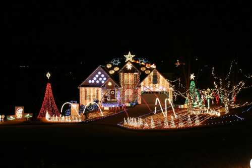 A beautifully decorated house with colorful Christmas lights, featuring trees, stars, and festive displays at night.