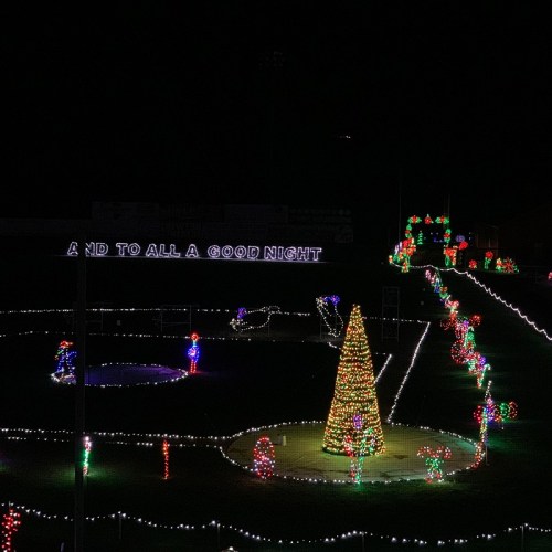 Colorful Christmas lights illuminate a festive scene with a tree, decorations, and a sign reading "AND TO ALL A GOOD NIGHT."