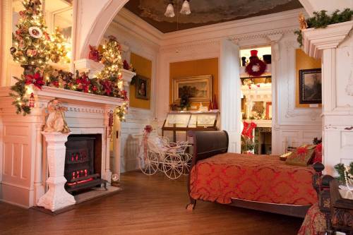 Cozy holiday-themed room with a decorated fireplace, a vintage bed, and festive decorations throughout.