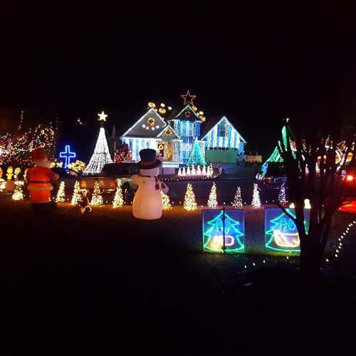 A festive display of colorful Christmas lights, decorations, and a snowman in a nighttime setting.