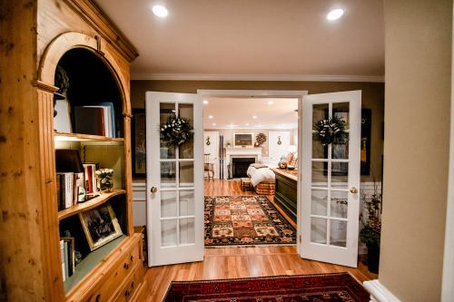 Cozy interior view of a room with double doors, bookshelves, and a warm, inviting atmosphere.