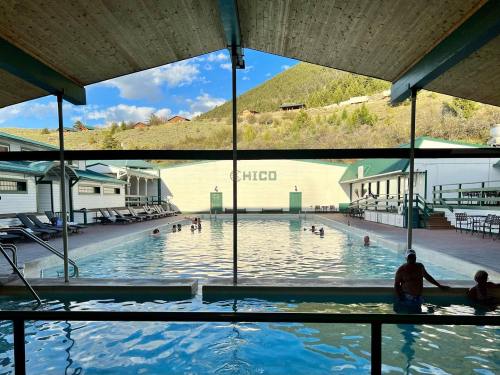 Indoor pool with people swimming, surrounded by mountains and a building labeled "CHICO" in the background.