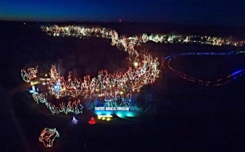 Aerial view of a festive display with colorful holiday lights winding through a dark landscape.
