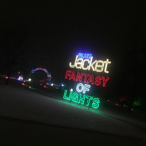 Neon sign reading "Blue Jacket Fantasy of Lights" illuminated in a snowy night setting.