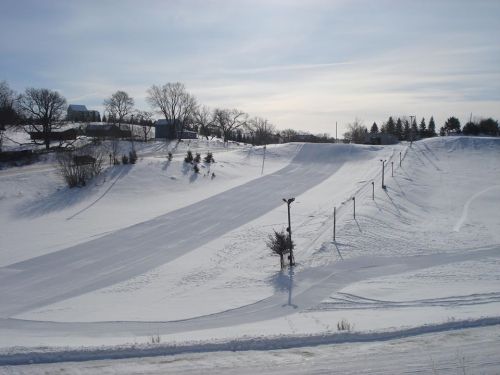 A snowy landscape featuring ski slopes, trees, and a clear blue sky.
