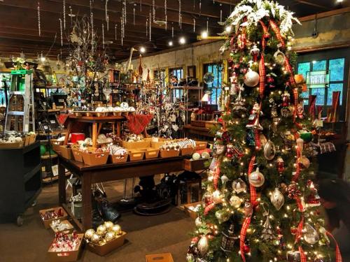 A cozy shop filled with holiday decorations, featuring a beautifully adorned Christmas tree and various ornaments.