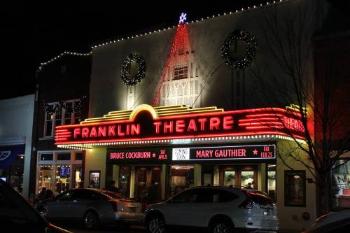 The illuminated Franklin Theatre at night, adorned with holiday decorations and a star on top.