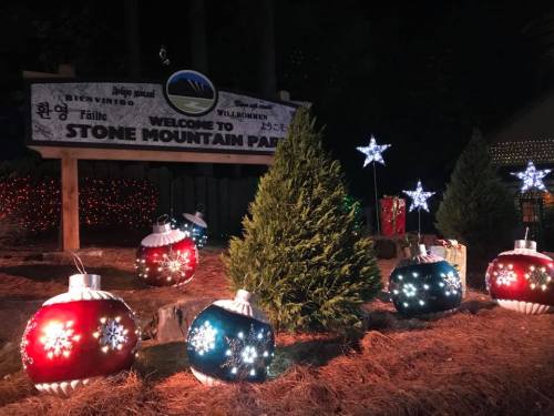 Colorful holiday ornaments and stars decorate the entrance to Stone Mountain Park, illuminated at night.