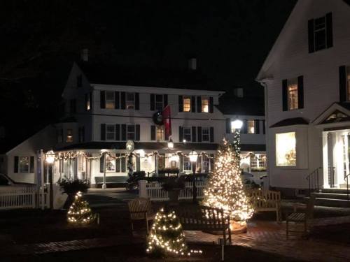 A charming night scene of a decorated building with Christmas lights and trees in a cozy, festive atmosphere.