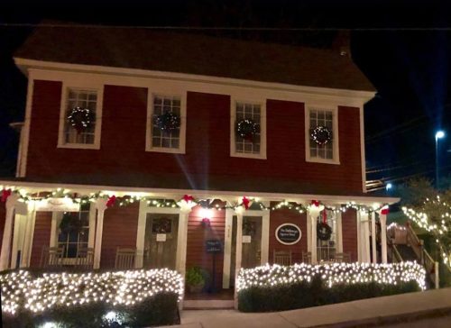 A festive building decorated with holiday lights, announcing closure from December 23-26 and reopening on December 27.