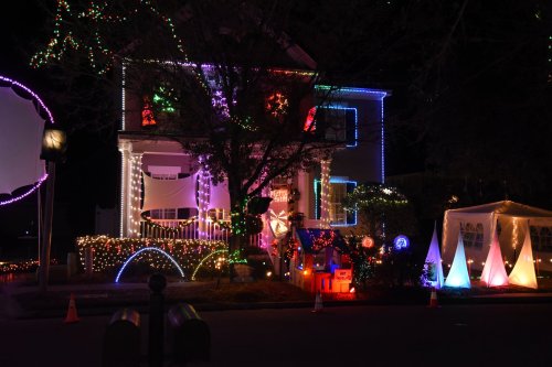 A brightly lit house decorated with colorful Christmas lights and festive displays at night.