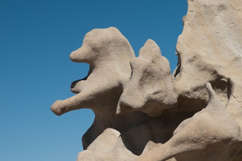 A weathered rock formation resembling a lion against a clear blue sky.