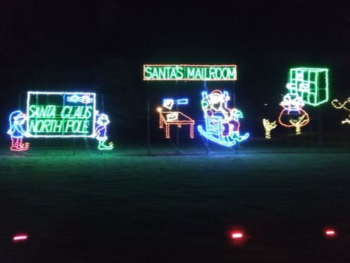 Colorful holiday lights depicting Santa's Mailroom and North Pole scenes, with festive characters and decorations.