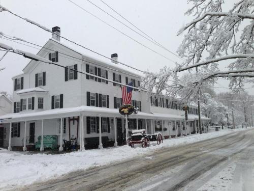 A snowy scene of a white building with an American flag, surrounded by snow-covered trees and a quiet street.