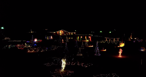 A festive display of colorful Christmas lights illuminating trees and buildings at night.