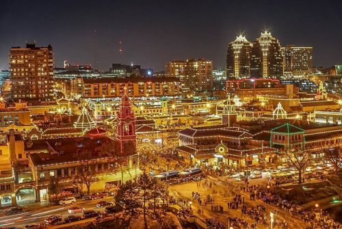 A vibrant cityscape at night, adorned with colorful holiday lights and bustling crowds in a festive atmosphere.