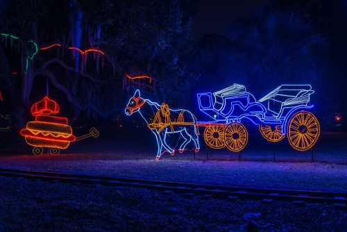 Neon light display featuring a horse-drawn carriage and a colorful carousel in a nighttime setting.