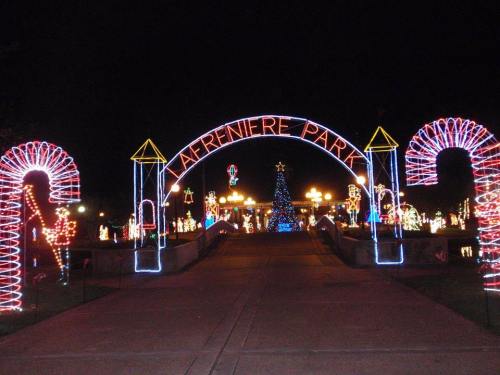 Colorful holiday lights illuminate the entrance to Lafreniere Park at night, featuring candy cane decorations and a Christmas tree.