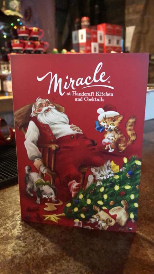A festive menu featuring Santa in a chair surrounded by playful animals and holiday decorations.